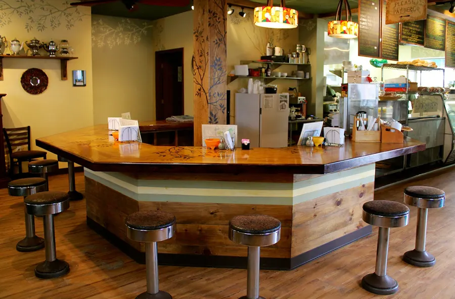 Wooden counter with stools and the deli case at Fressers Delicatessen