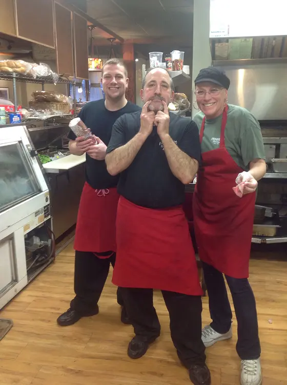 Three of the Fressers crew in aprons behind the deli counter